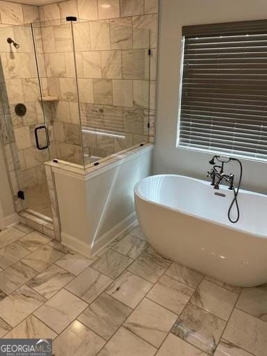 full bathroom featuring marble finish floor, a shower stall, and a freestanding tub