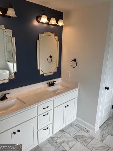 full bathroom with marble finish floor, double vanity, a sink, and baseboards