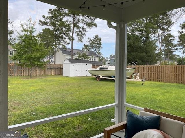 view of yard featuring an outbuilding, a fenced backyard, and a storage unit