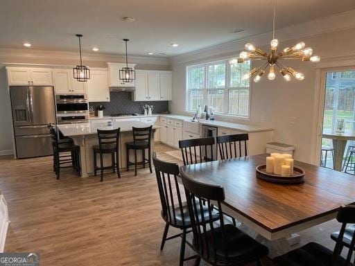 dining area with light wood-style floors, recessed lighting, and crown molding