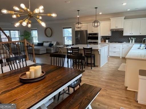 dining space featuring recessed lighting, stairway, ornamental molding, a chandelier, and light wood-type flooring