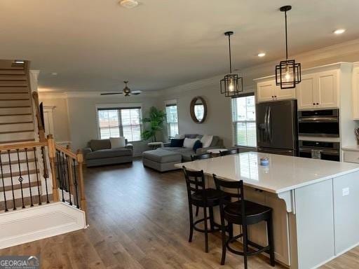 kitchen featuring wood finished floors, white cabinetry, light countertops, freestanding refrigerator, and crown molding