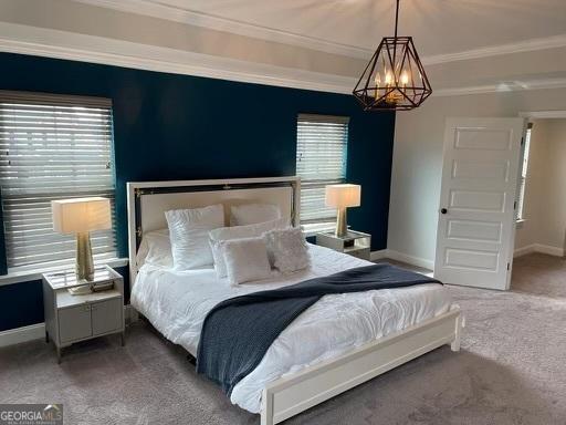 carpeted bedroom with a chandelier, baseboards, and crown molding