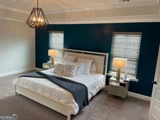 carpeted bedroom with ornamental molding, an inviting chandelier, a raised ceiling, and baseboards