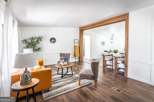 living area with visible vents, a decorative wall, and wood finished floors