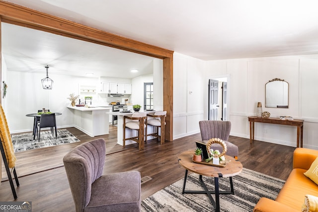 living room featuring visible vents, a decorative wall, and dark wood-style flooring