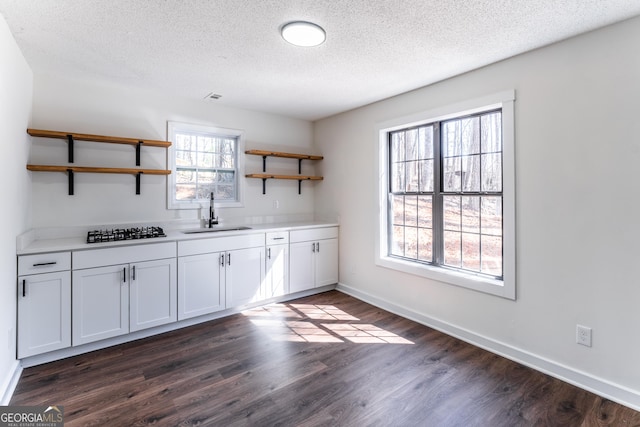 kitchen with baseboards, dark wood finished floors, open shelves, a sink, and black gas stovetop