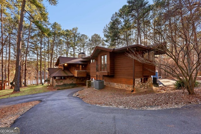 view of home's exterior featuring driveway, a chimney, and cooling unit