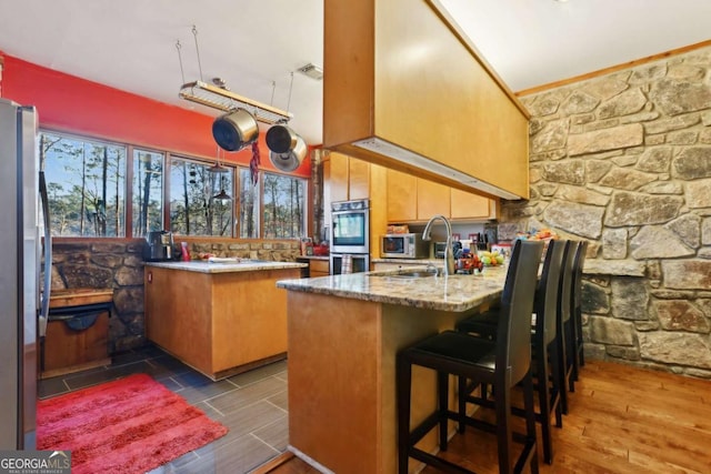 kitchen with a peninsula, visible vents, appliances with stainless steel finishes, and a sink