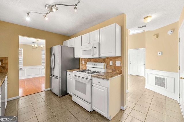 kitchen with white cabinetry, white appliances, visible vents, and light tile patterned floors