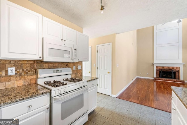 kitchen with white appliances, light tile patterned floors, a fireplace, and backsplash