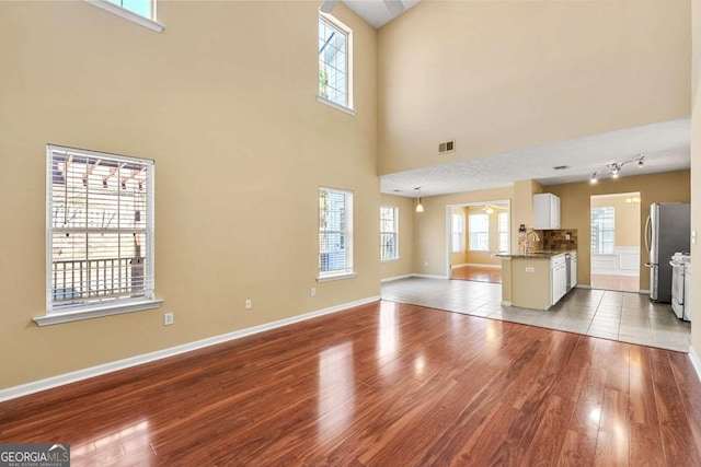 unfurnished living room with wood finished floors, visible vents, and baseboards