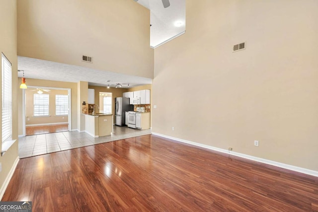 unfurnished living room with visible vents, a ceiling fan, and wood finished floors