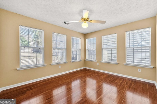 spare room featuring ceiling fan, baseboards, dark wood finished floors, and a textured ceiling