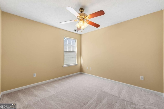 empty room featuring carpet floors, visible vents, baseboards, and ceiling fan