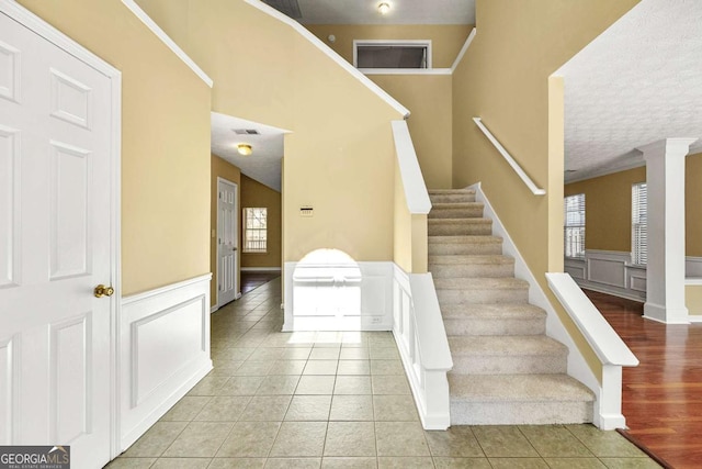 stairway featuring tile patterned flooring, a wealth of natural light, and wainscoting