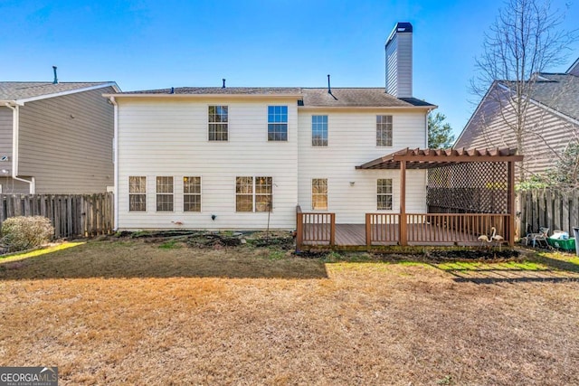 rear view of house with a fenced backyard, a chimney, a deck, and a yard