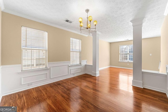 unfurnished room featuring visible vents, ornate columns, and wood finished floors