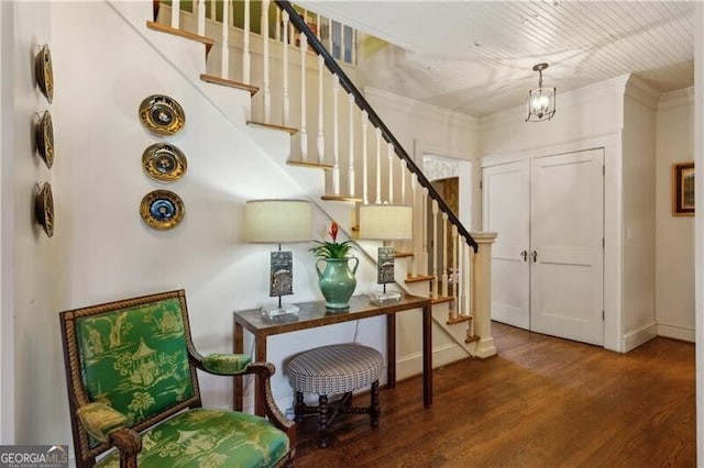 foyer with stairs, a chandelier, crown molding, and wood finished floors