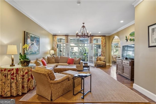 living area featuring dark wood-style floors, arched walkways, crown molding, a chandelier, and baseboards