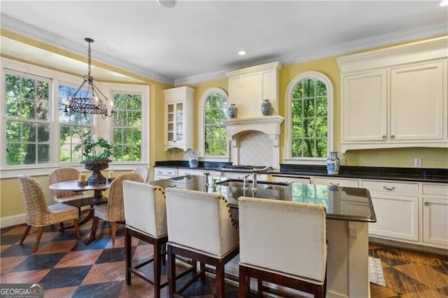 kitchen featuring ornamental molding, dark countertops, hanging light fixtures, and plenty of natural light