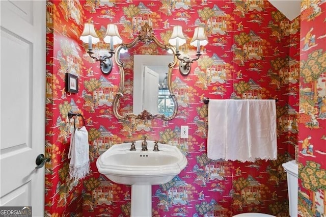 half bathroom featuring wallpapered walls