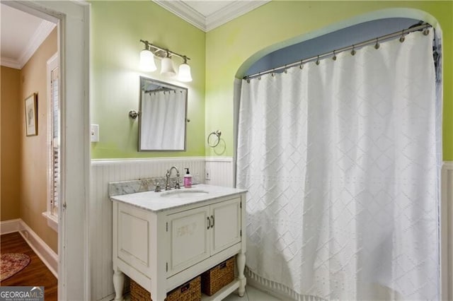 full bathroom featuring ornamental molding, wainscoting, vanity, and wood finished floors