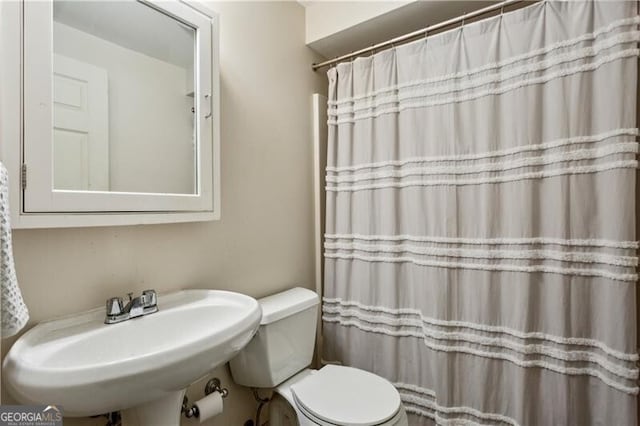 full bath featuring curtained shower, a sink, and toilet