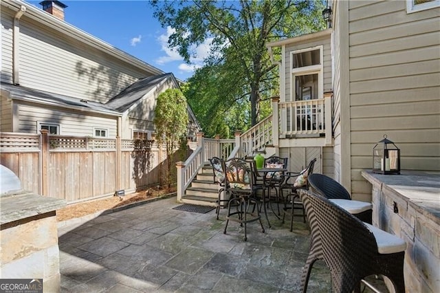 view of patio with stairs and fence