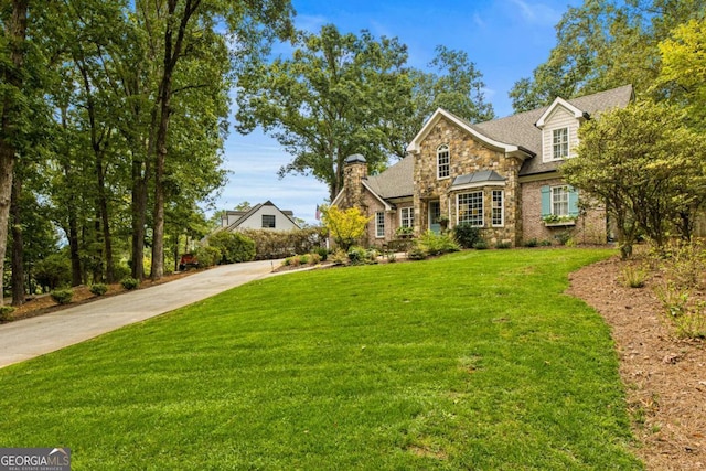 traditional-style home with stone siding, a front lawn, and driveway