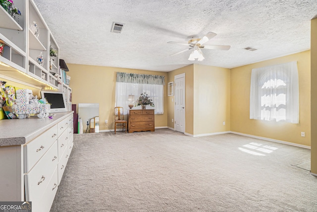 interior space featuring light carpet, ceiling fan, visible vents, and baseboards