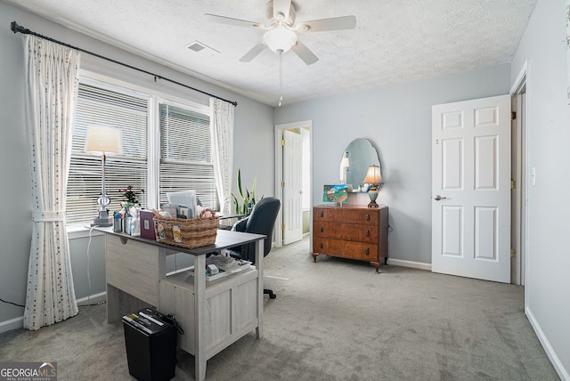 office area with carpet floors, a healthy amount of sunlight, visible vents, and a textured ceiling