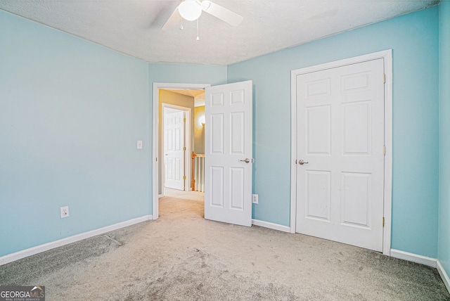 unfurnished bedroom featuring a ceiling fan, carpet, a textured ceiling, and baseboards