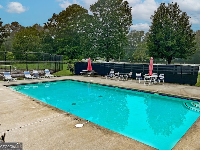 community pool with fence and a patio