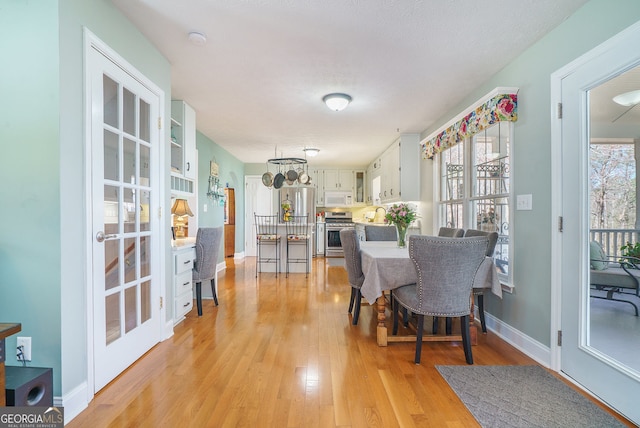 dining area with light wood-style floors, plenty of natural light, and baseboards