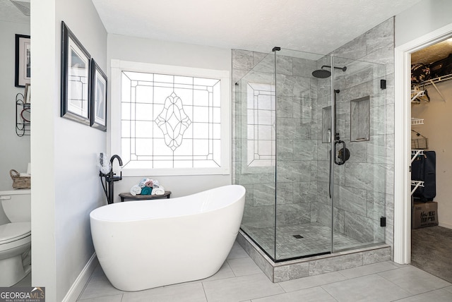 full bath featuring toilet, visible vents, a freestanding bath, a spacious closet, and a stall shower