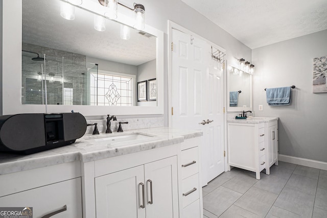 full bath with a stall shower, a sink, and a textured ceiling