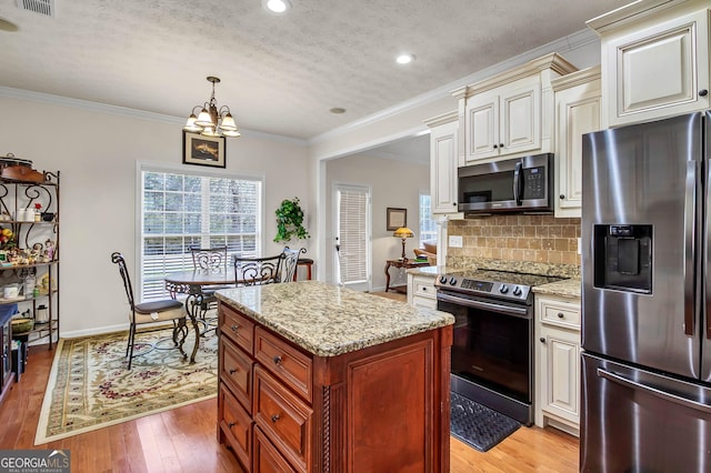 kitchen with tasteful backsplash, light stone countertops, cream cabinets, stainless steel appliances, and light wood-style floors