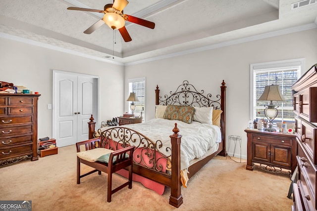 bedroom featuring a raised ceiling, light carpet, visible vents, and a textured ceiling