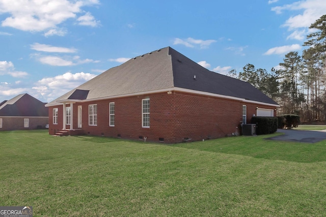 view of side of property with a lawn, crawl space, an attached garage, cooling unit, and brick siding