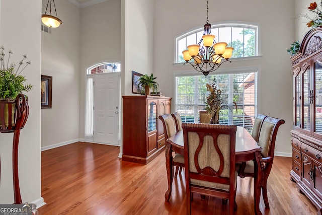 dining room with a chandelier, light wood finished floors, a high ceiling, and baseboards