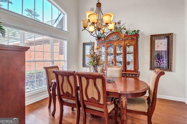 dining area featuring plenty of natural light, baseboards, a chandelier, and wood finished floors