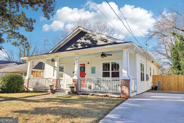 bungalow-style house with covered porch, ceiling fan, a front yard, and fence