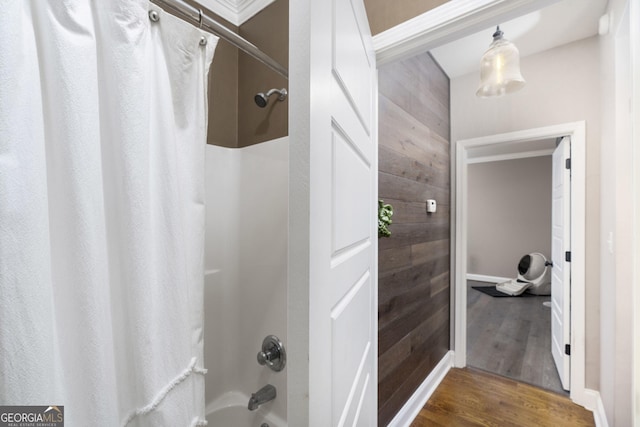 bathroom featuring wood walls, shower / bath combo, and wood finished floors