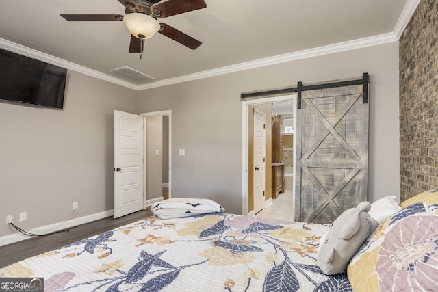 bedroom featuring ornamental molding, wood finished floors, baseboards, and a barn door