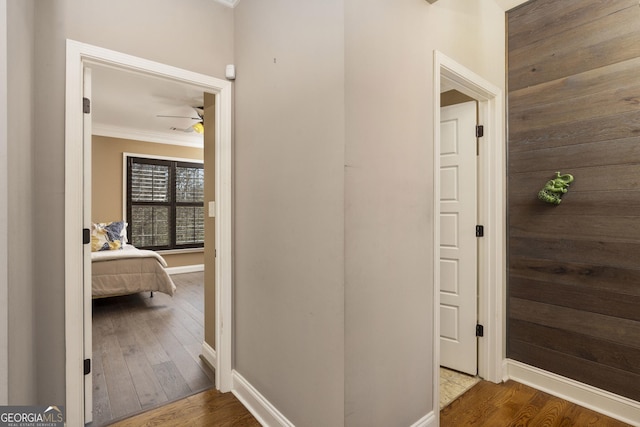 corridor featuring ornamental molding, hardwood / wood-style floors, and baseboards