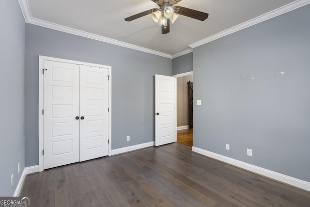 unfurnished bedroom with dark wood-type flooring, a ceiling fan, baseboards, a closet, and crown molding