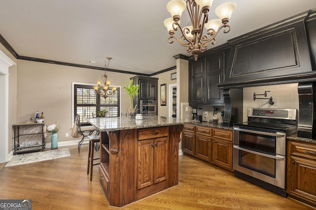 kitchen featuring dark stone counters, range with two ovens, light wood-style floors, and a notable chandelier