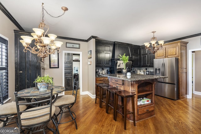 kitchen featuring a chandelier, a center island, stainless steel refrigerator with ice dispenser, and wood finished floors