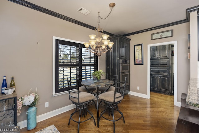 dining space featuring dark wood-style flooring, visible vents, ornamental molding, a chandelier, and baseboards